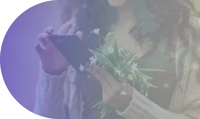 Woman holding a flower while scrolling through her mobile device